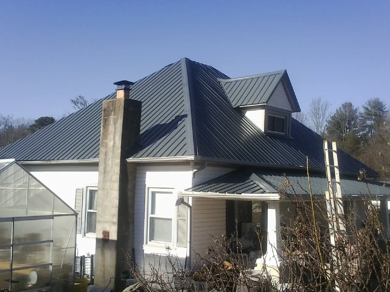 Dark blue standing seam metal roof on a white farmhouse with dormer — Slate & Tile Roof Repair by Roofing Brothers in Dewar