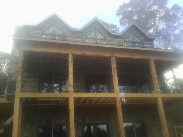 Dormers and porch framing on a large log home under construction — Roof Coating work by our crew in Dewar