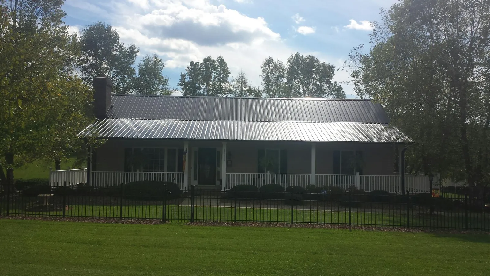 Gray metal roof on a brick ranch with a full width front porch — Gutter Guard Installation work by our crew in Dewar